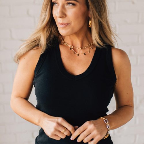 BLONDE WOMAN WEARING A BASIC DYED COTTON V-NECK RIBBED TANK WITH SCOOP V-NECKLINE.