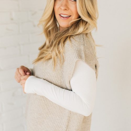 BLONDE WOMAN WEARING AN OVERSIZED SWEATER VEST WITH SIDE SLIT