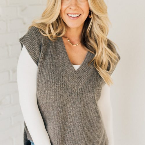 BLONDE WOMAN WEARING AN OVERSIZED SWEATER VEST WITH SIDE SLIT