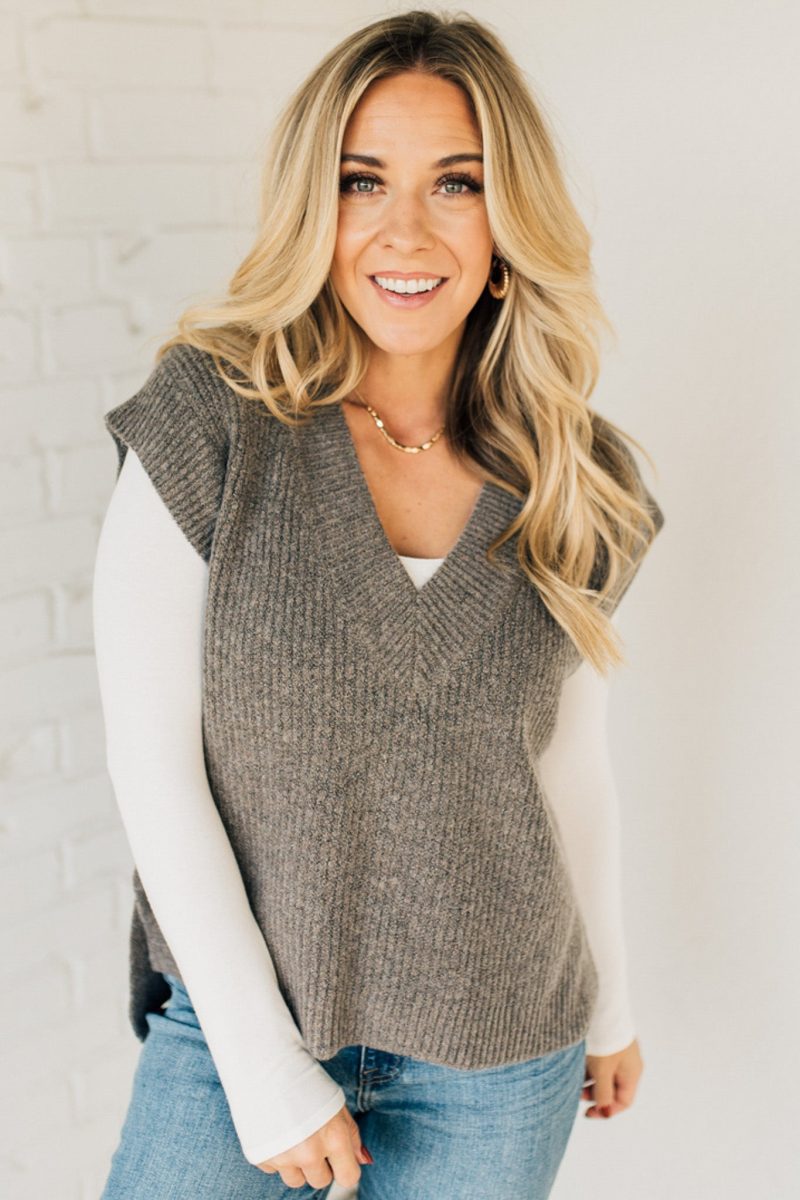 BLONDE WOMAN WEARING AN OVERSIZED SWEATER VEST WITH SIDE SLIT