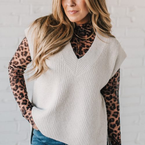 BLONDE WOMAN WEARING AN OVERSIZED SWEATER VEST WITH SIDE SLIT