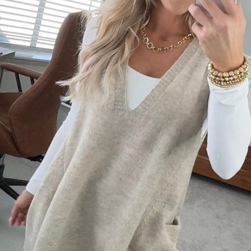 BLONDE WOMAN WEARING AN OVERSIZED V-NECK LONG SOFT SWEATER VEST WITH SIDE POCKETS.