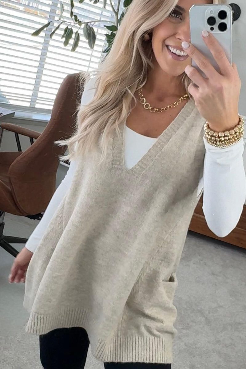 BLONDE WOMAN WEARING AN OVERSIZED V-NECK LONG SOFT SWEATER VEST WITH SIDE POCKETS.