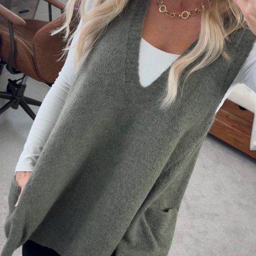 BLONDE WOMAN WEARING AN OVERSIZED V-NECK LONG SOFT SWEATER VEST WITH SIDE POCKETS.