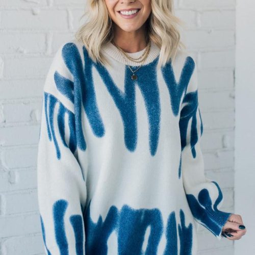 woman wearing an oversized sweater in a trendy ivory and blue graffiti print