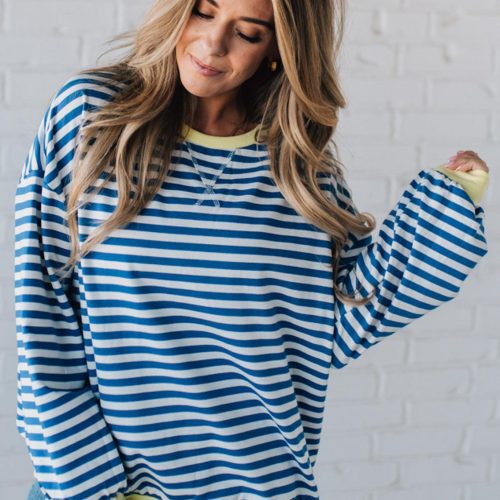 girl modeling a long sleeve oversized striped top with contrasting color on the sleeve cuff, neckline and hem