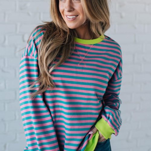 girl modeling a long sleeve oversized striped top with contrasting color on the sleeve cuff, neckline and hem